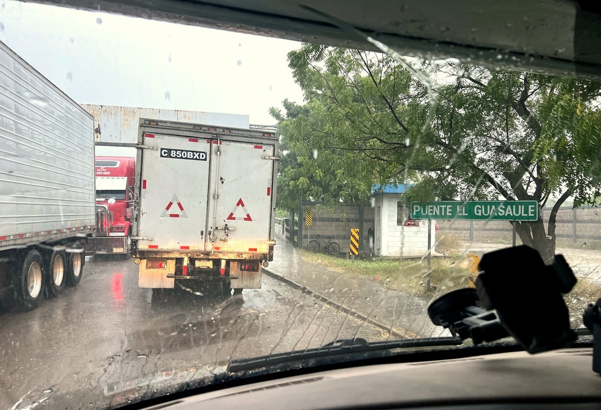 Rain-soaked view from the windshield of a truck queue at the Puente El Guasaule border into Nicaragua