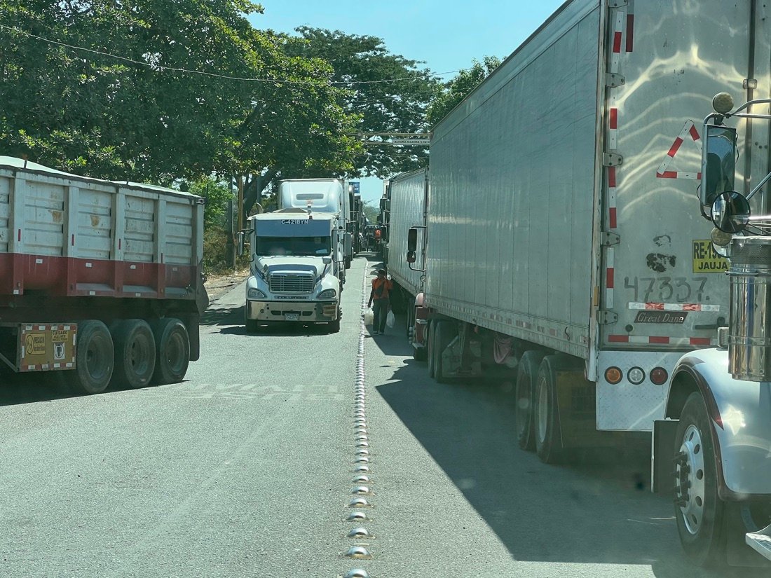 A long line of semi trucks waiting at a Central American border crossing